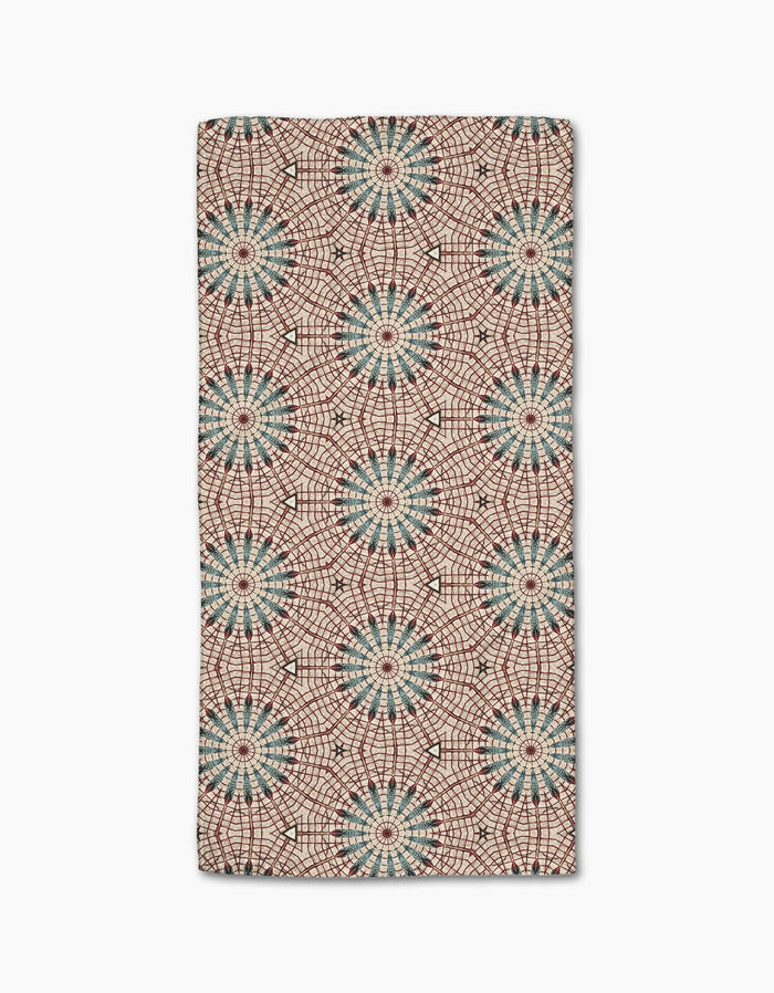 The Katherine Berkeley Blue Aster Foxtrot Bar Towel features ultra-absorbent Geoweave fabric and a kaleidoscopic pattern of blue and red starbursts on beige for a bold, symmetrical look.