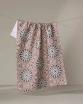 The Katherine Berkeley Blue Aster Foxtrot kitchen towel, featuring blue and red geometric starburst patterns and made from recycled materials, hangs on a clothesline against a plain, neutral background.