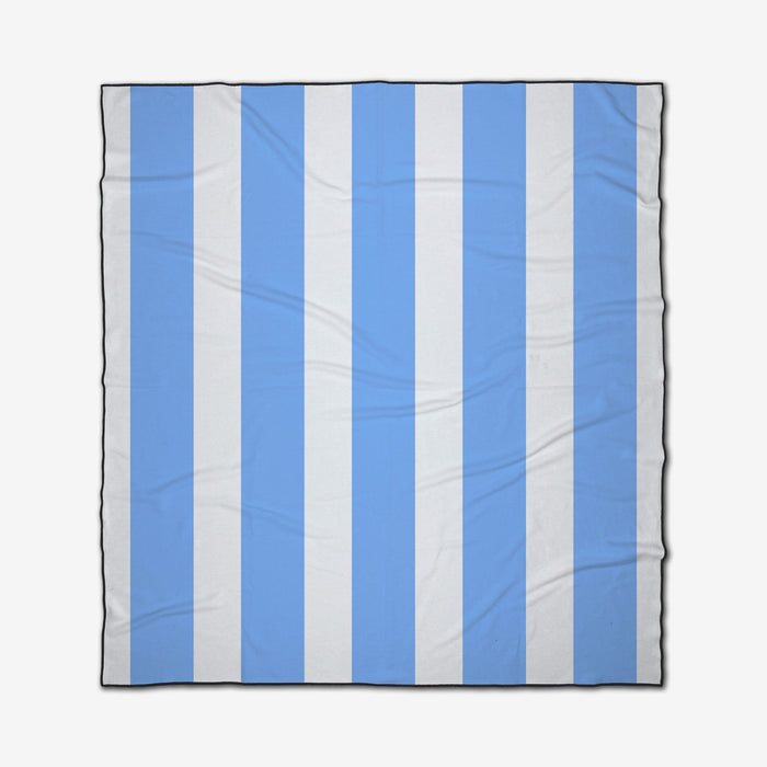 The GEOMETRY Blue Block Stripes is a square beach blanket with alternating vertical light blue and white stripes, black-bordered edges for style, made from recycled materials with slight folds and creases.