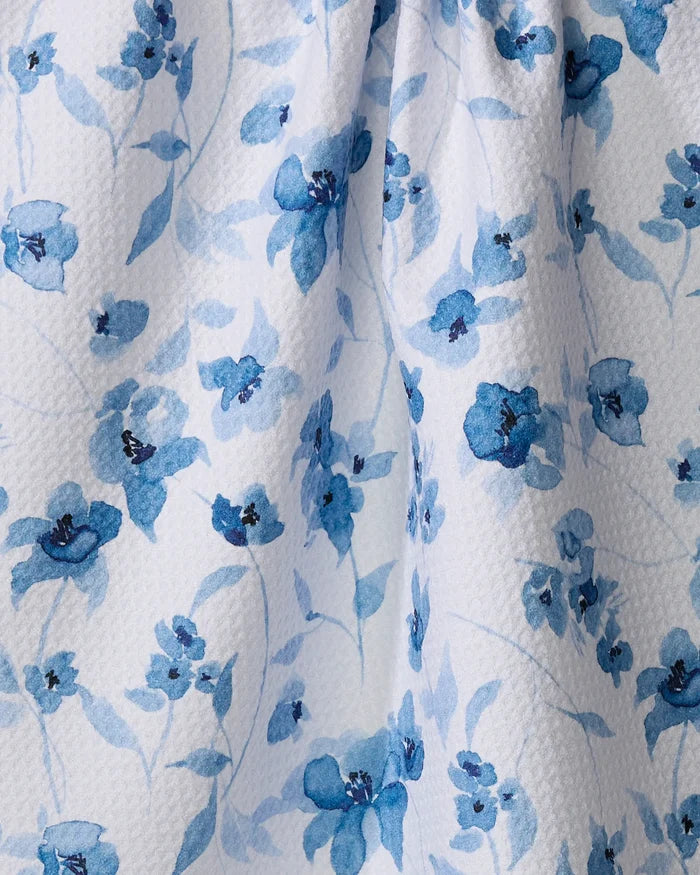 Aubrey Fairchild’s Blue Floral tea towel features a white textured fabric with watercolor-style blue flowers and leaves, absorbing spills while adding elegance to your kitchen.