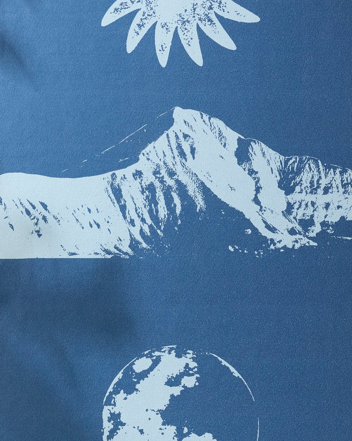 Blue Moon by Graphics and Grain: a minimalist mountain range in white on blue, with a stylized sun above and partial moon below—perfect inspiration for your non-slip yoga towel.