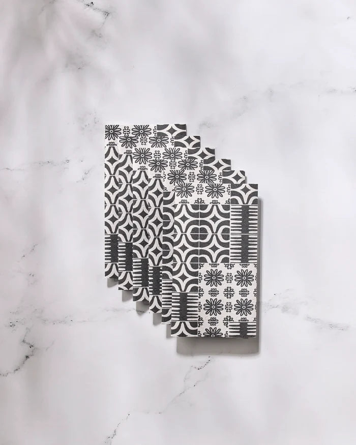 Five Bohemian Mosaic reusable paper towels by GEOMETRY, featuring black and white geometric and floral designs, are neatly fanned out on a white marble surface.