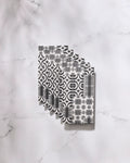 Five Bohemian Mosaic reusable paper towels by GEOMETRY, featuring black and white geometric and floral designs, are neatly fanned out on a white marble surface.
