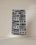 The GEOMETRY Bohemian Mosaic bar towel, crafted from recycled materials, showcases black and white geometric and floral patterns as it hangs from a clothesline against a beige background—a stylish, sustainable choice.