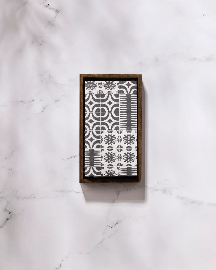 The GEOMETRY Bohemian Mosaic rectangular tray, featuring a black and white geometric and floral design, rests on white marble beside a roll of eco-friendly paper towels.