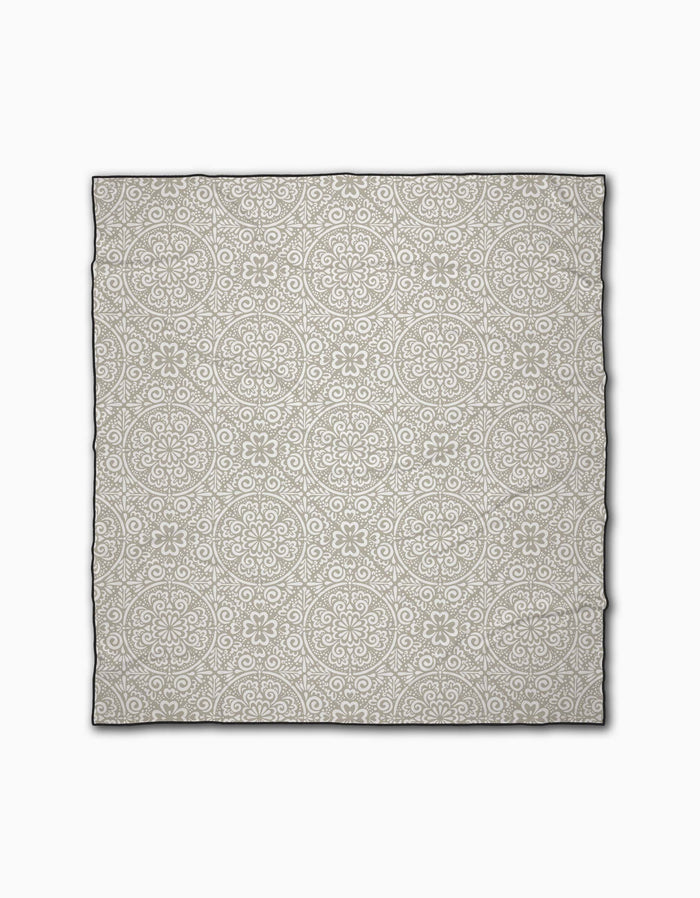 The Boho Medallion beach blanket by Kris Ruff features a light gray background with a white floral and geometric circular pattern. Crafted from quick-drying recycled materials, it delivers comfort and eco-friendly style.