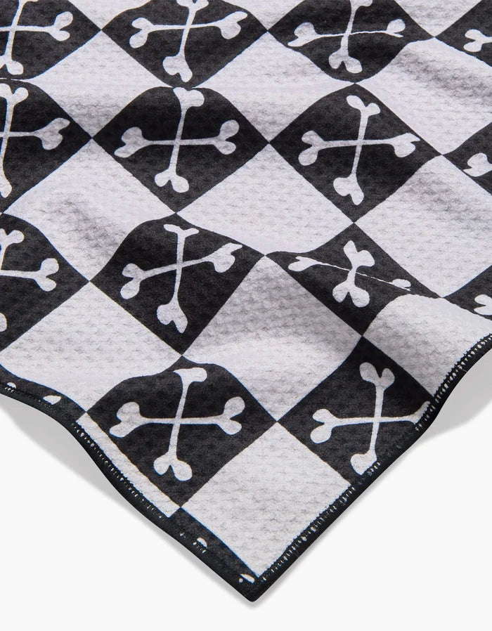 A close-up of the Boneyard Black Checkerboard dog towel by Charlie Rowan Designs, featuring crossed bones in each square, a textured and highly absorbent surface, and neatly stitched edges.
