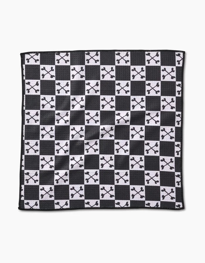 The Boneyard White Checkerboard by Charlie Rowan Designs is crafted from recycled materials and features alternating solid white squares with black squares adorned by a white abstract branched pattern.