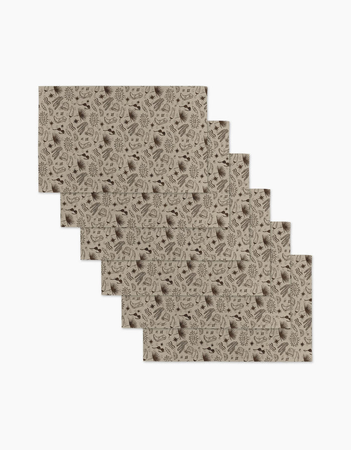 Six beige rectangular Bonfire Nights placemats by Geometry are stacked in a staggered pile. Reusable and eco-friendly, each features dark brown leaves and branches on white—sustainable, not paper towels.