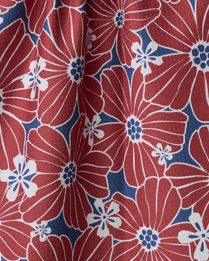 A close-up of the Ashley Celena "Botanical Blush" tea towel—ultra-absorbent, made from recycled materials, with large red flowers, blue centers, white outlines, small white blooms, all on a blue background.
