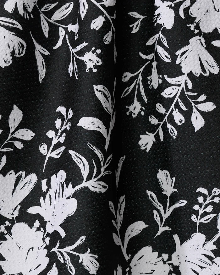 Botanical Silhouettes Charcoal by Danelys Sidron features white floral and leaf patterns on a black textured background—ideal for a stylish, recycled-material tea towel.