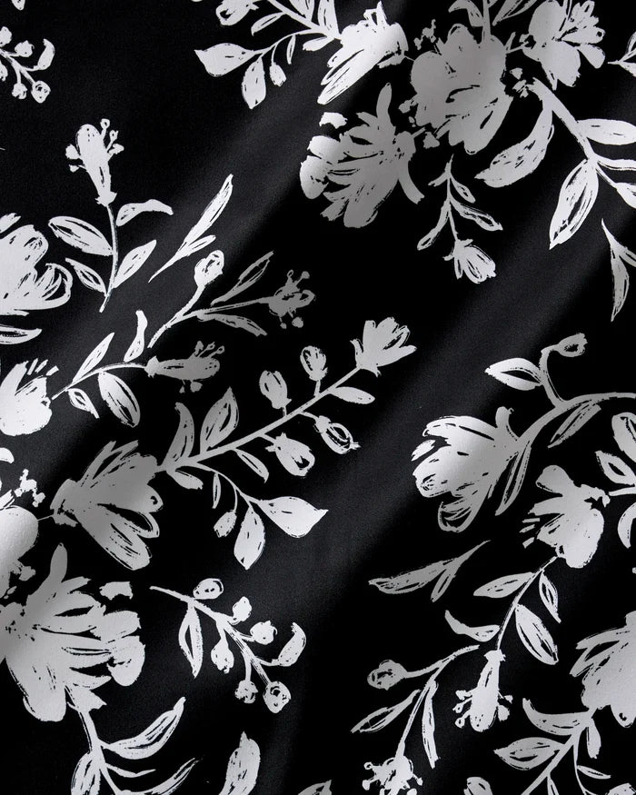 Botanical Silhouettes Charcoal by Danelys Sidron features black fabric with white, stylized floral prints. Its subtly wrinkled texture adds elegance—ideal for a recycled dinner napkin or Dinner Napkin Set.