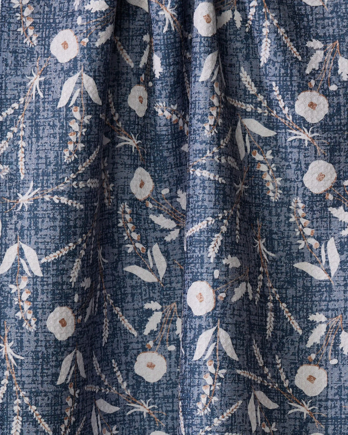 The Boyce Blue dish towel by Becki Owens features a textured blue fabric with white and light brown flowers, light green leaves, and delicate stems in a repeating botanical design. Softly gathered, it's both absorbent and stylish for your kitchen.