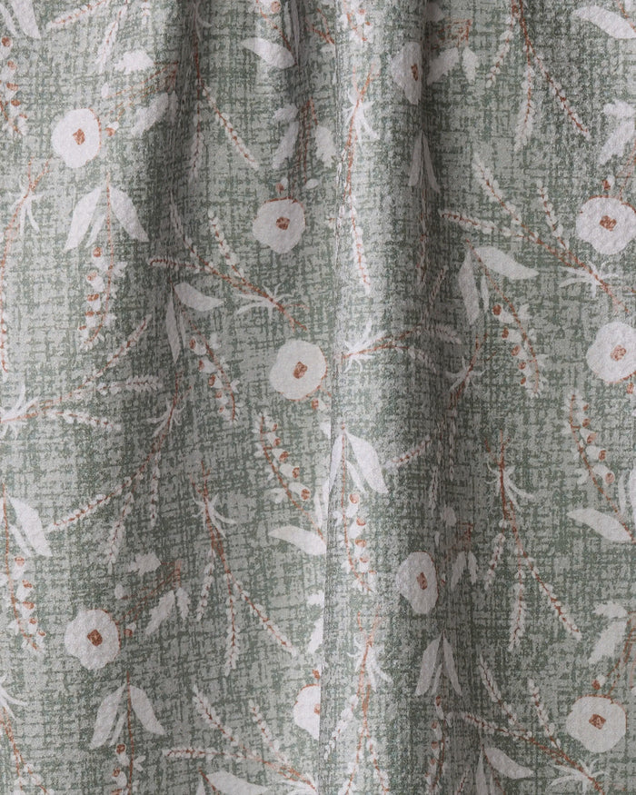 A close-up of Boyce Sage by Becki Owens shows green recycled fabric with a textured background, featuring a white floral and leaf pattern accented by brown stems and small dots.