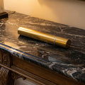 Bronze scattering tube on a dark marble surface