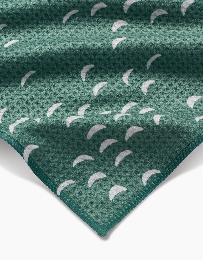 A close-up of the Jessica Swift Breezeway bar towel shows its green Geoweave fabric, white crescent patterns, and neatly stitched edge.