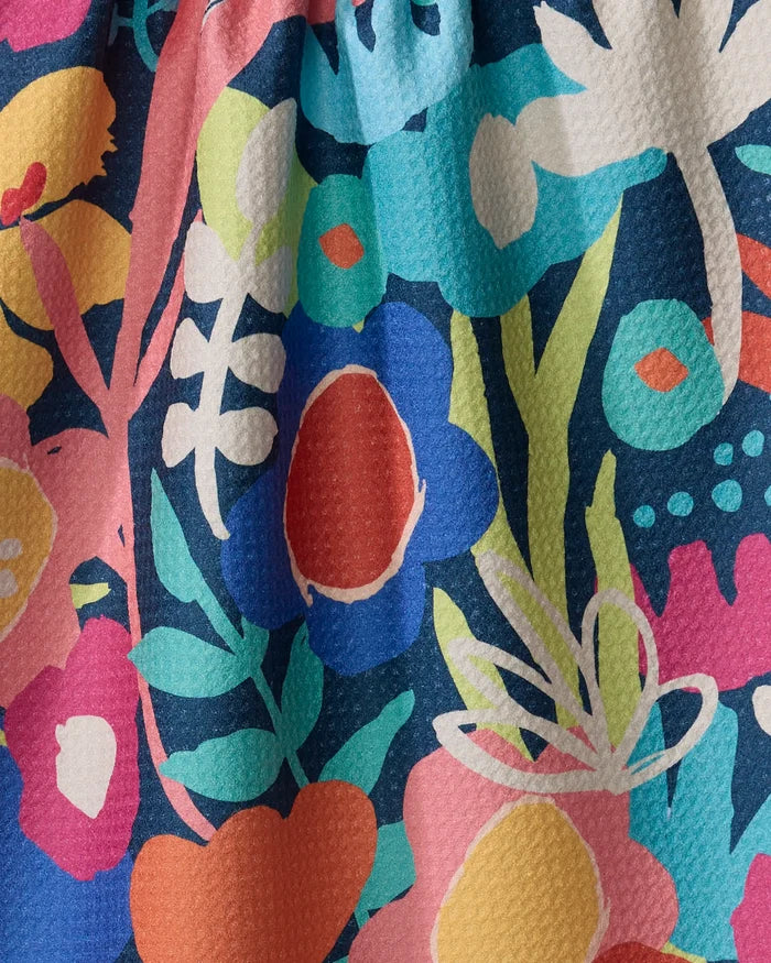Bright Bunch by Sareka Unique is a colorful recycled kitchen or tea towel featuring bold floral shapes in blue, red, yellow, green, white, and pink on a dark blue textured background—adding playful style to your space.