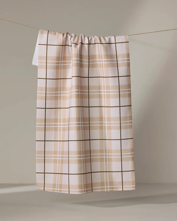The "Brown Sugar" curtain by Purely Kaylie, featuring a beige and white plaid and gathered top, hangs on a clothesline against a light background.