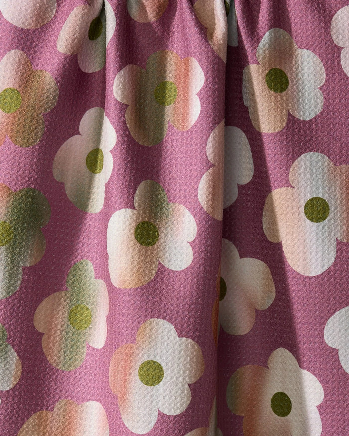 Close-up of the Geometry Brushed Bouquet towel, featuring ultra-absorbent textured fabric with white, green, and peach stylized flowers on a pink background. The kitchen tea towel appears slightly gathered at the top.