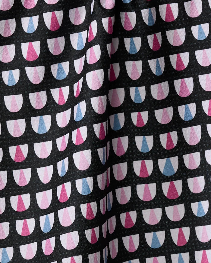 A close-up of Bug Boogie by Anette Heiberg, a recycled kitchen towel featuring white, pink, and blue semi-circles on black. The textured fabric is folded and highly absorbent—ideal for use as a dish towel.