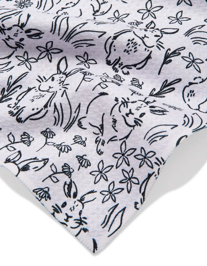 A close-up of Bunny Rabbit Garden by Charlie Rowan Designs shows a playful black line drawing of rabbits, flowers, and grass on a light grey recycled fabric.