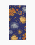 The Geometry Bursting Skies Blue rectangular bar towel showcases a navy background with orange, yellow, blue, and white fireworks-like bursts on Geoweave fabric.
