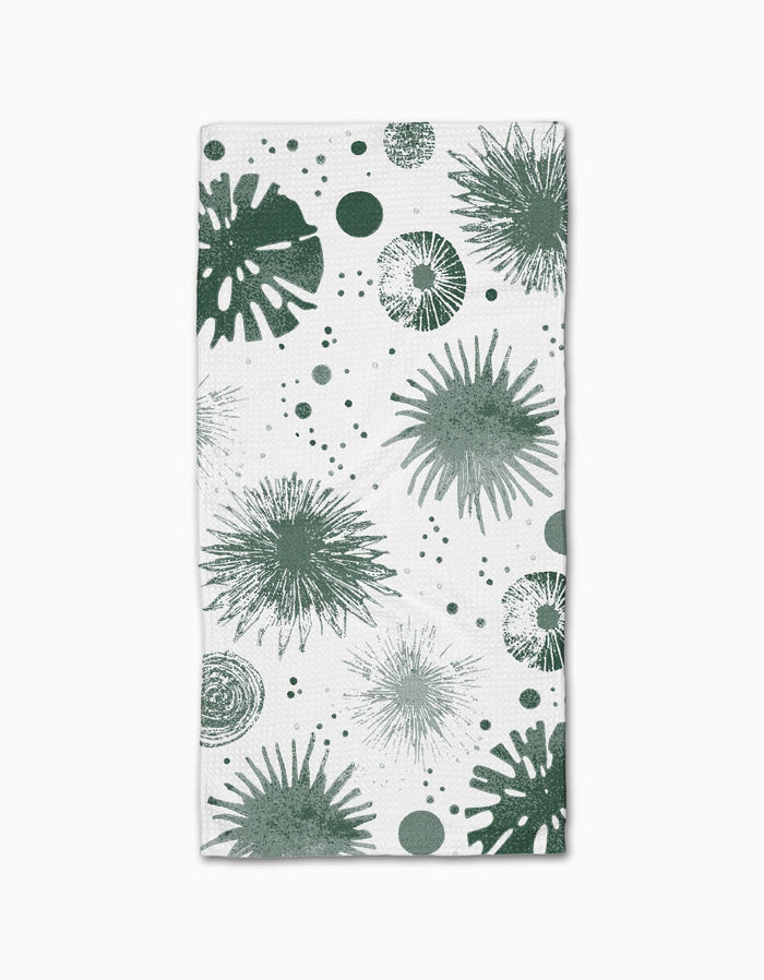 The Geometry Bursting Skies Green is a white rectangular bar towel, made from recycled materials, featuring playful green abstract sea urchins and dotted shapes for a marine-inspired look.