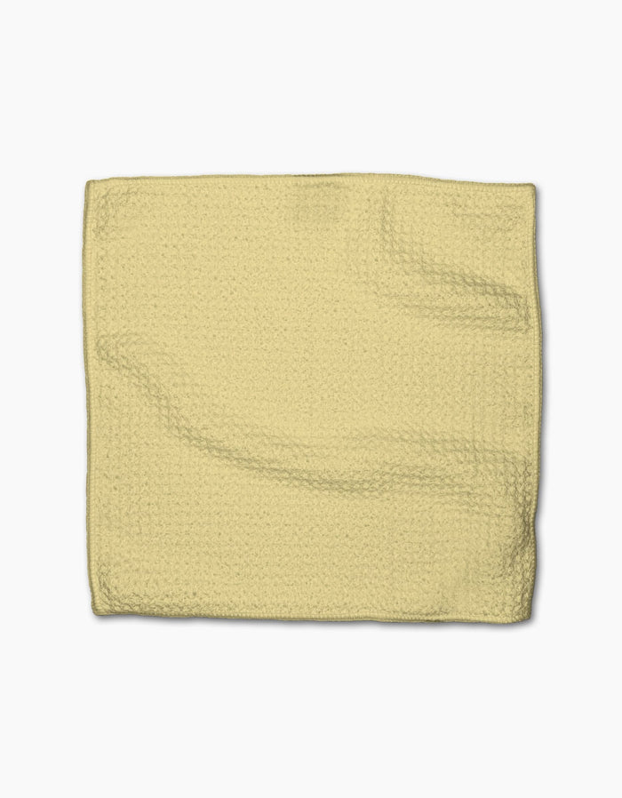 A folded GEOMETRY Butter Yellow dishcloth made from textured Geoweave fabric is laid flat on a white background.