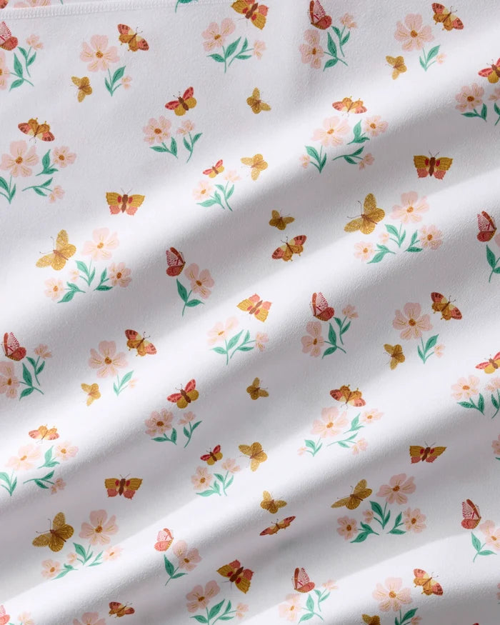 The Butterfly Garden napkin by Danelys Sidron features white fabric with pink flowers, green leaves, and orange-yellow butterflies. Softly wrinkled and absorbent, it's ideal for any Dinner Napkin Set or as recycled dinner napkins.