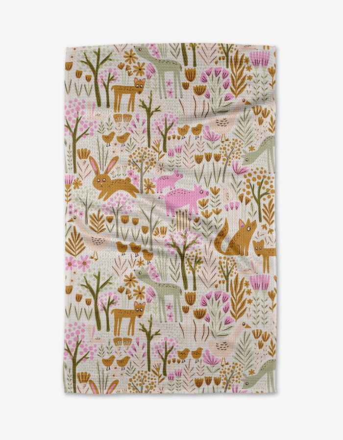 The Callalight tea towel by Amy MacCready showcases a whimsical woodland print with deer, rabbits, foxes, boars, hedgehogs, and florals in brown, pink, and green on cream—crafted from ultra-absorbent recycled materials.