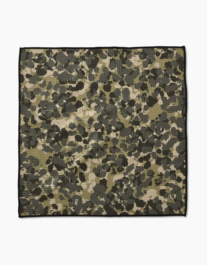 The Geometry Camo Paw Towel features a green, brown, and black camouflage pattern with a thin black border. Made from ultra-absorbent Geoweave fabric, it is shown flat on a white background.