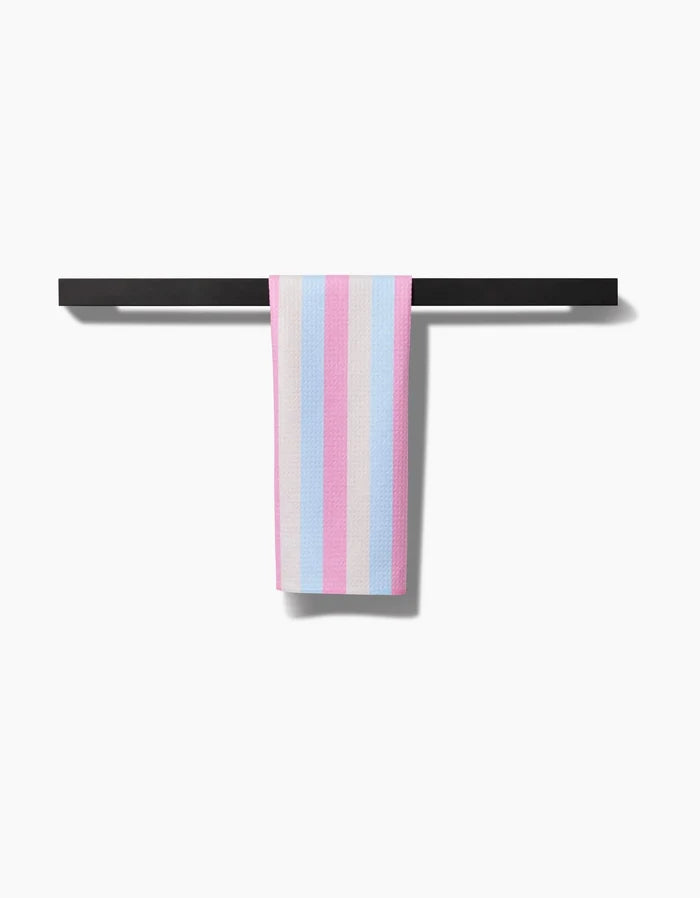 The Candy Pastels bar towel by Amy Droubay, made from ultra-absorbent Geoweave fabric, features vertical pastel blue, pink, and white stripes and hangs over a black bar against a white background.