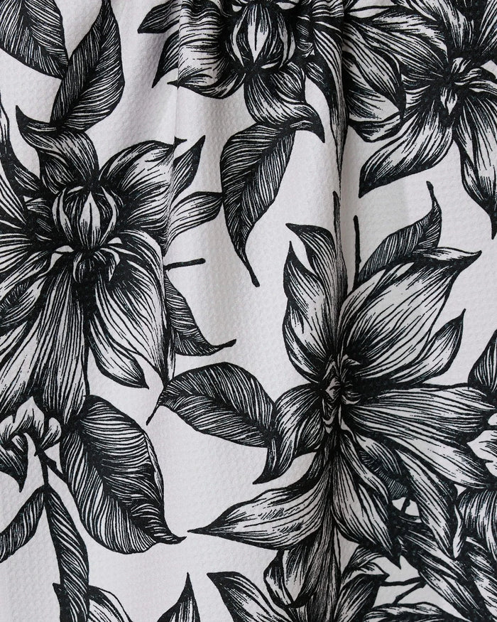 Black and white illustration of large, detailed flowers with leaves on a textured GEOMETRY Caring tea towel, crafted from ultra-absorbent recycled materials.