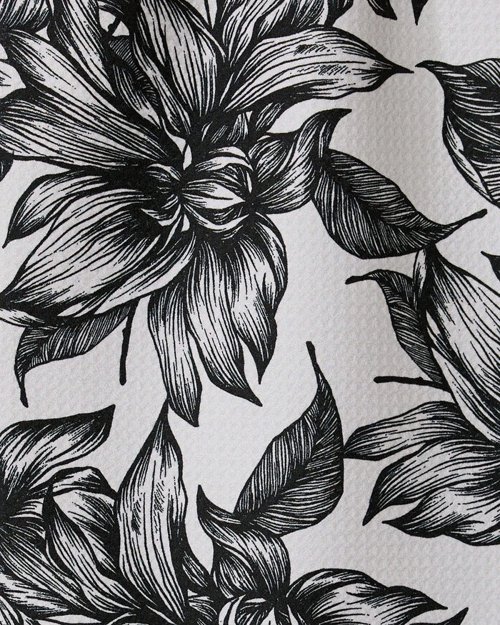 Black and white illustration of large, detailed flowers and leaves with intricate linework covers Caring by GEOMETRY, a textured recycled kitchen or bar towel.