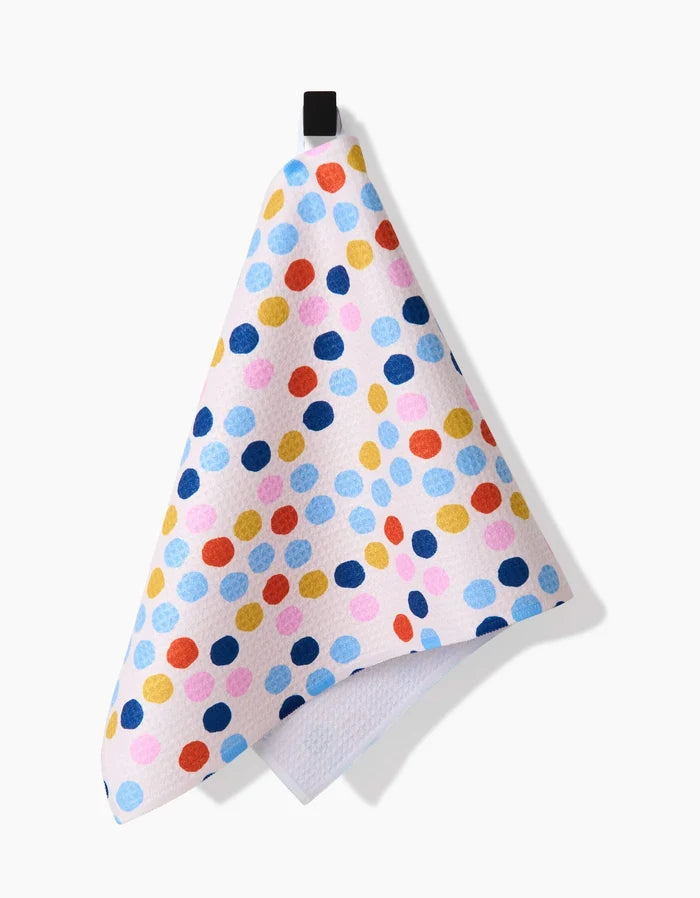 Carnival by Lizzie Clark: a white Bar Towel featuring blue, yellow, red, and pink polka dots, made from Geoweave fabric with a black hanging loop, shown against a white background.