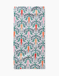 The Carrot Damask kitchen towel by Sarah Daugherty is made from white recycled fabric and features a vertical pattern of orange and pink carrots with green leafy tops, neatly arranged in rows.