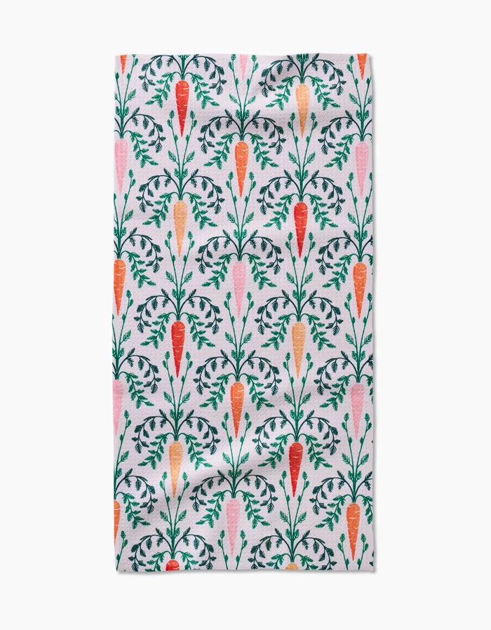 The Carrot Damask kitchen towel by Sarah Daugherty is made from white recycled fabric and features a vertical pattern of orange and pink carrots with green leafy tops, neatly arranged in rows.