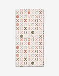 The Carys Light rectangular bar towel by Amy MacCready is made from recycled Geoweave fabric and showcases a repeating X and O pattern in red, brown, and beige on white for stylish sustainability.