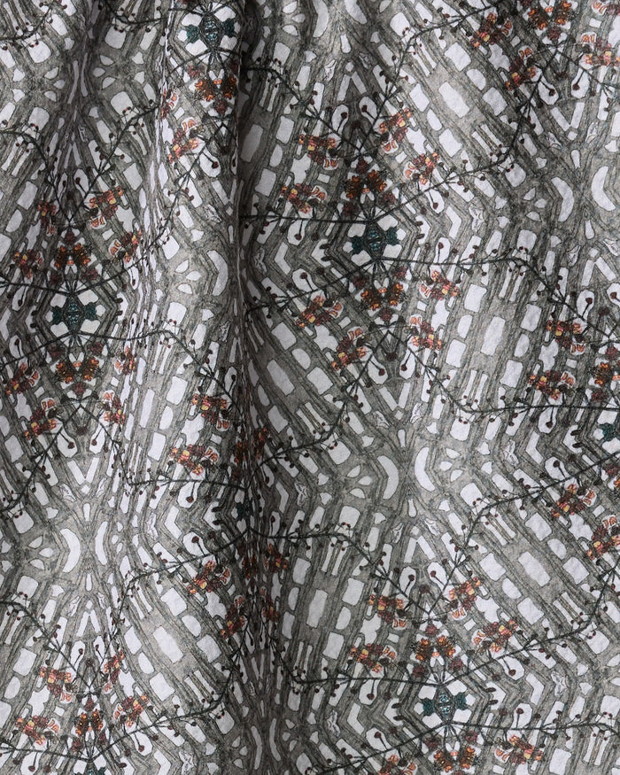 A close-up of the Katherine Berkeley Cha Cha Interchange tea towel, made from recycled materials, featuring a geometric diamond pattern with gray, white, black, and orange accents. The quick-drying fabric is slightly folded.