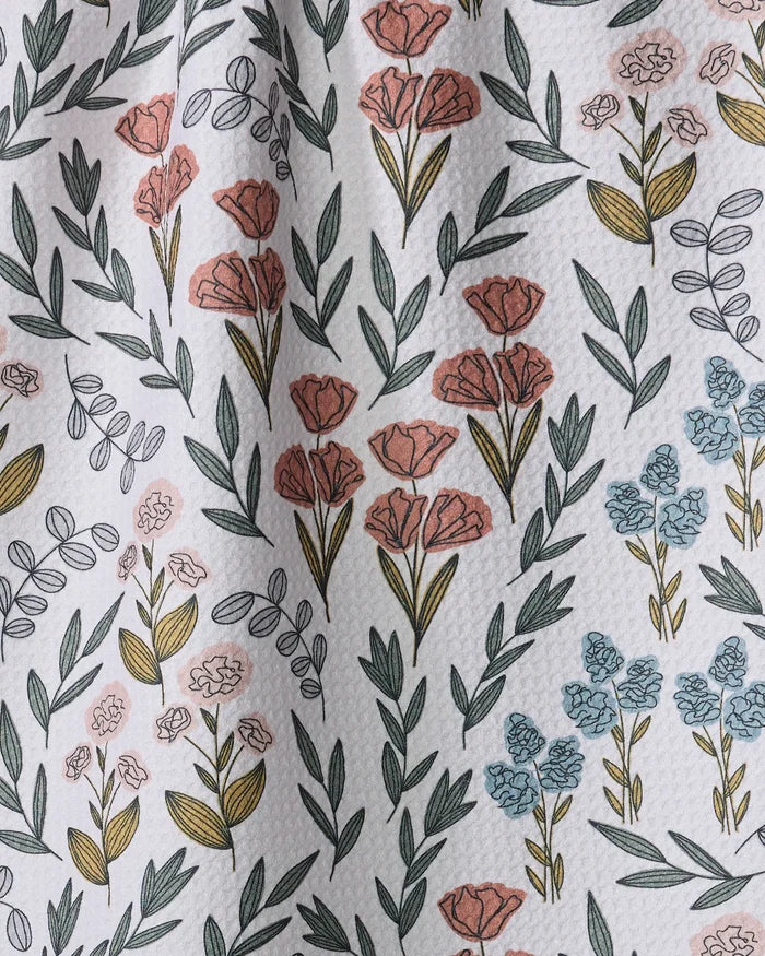 The Charolette Multi tea towel by Charlie Rowan Designs features a white textured fabric with pink, blue, and yellow flowers and green leaves in a repeating botanical pattern. Its ultra-absorbent surface has subtle wrinkles for added depth.