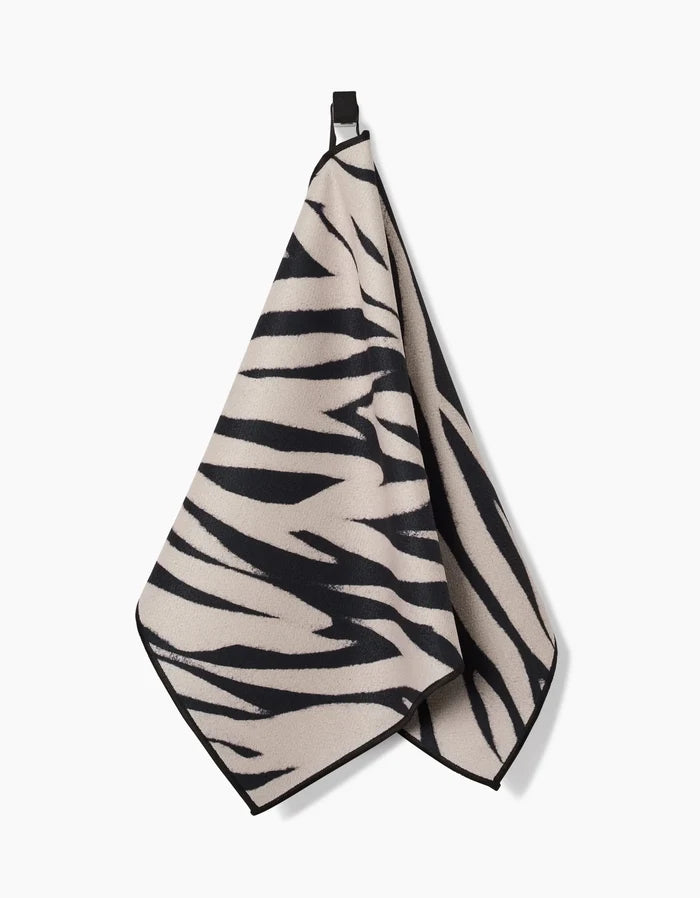 The Chase fitness towel by GEOMETRY features a black and beige zebra stripe design, is made from recycled materials, and is displayed on a white background.