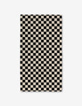 The GEOMETRY Checkered Luxe Bath Towel, featuring Geoweave technology and a black-and-white checkerboard pattern, offers an ultra-absorbent experience against a crisp white background.