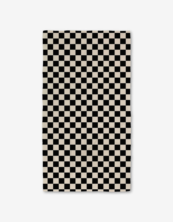 The GEOMETRY Checkered Luxe Bath Towel, featuring Geoweave technology and a black-and-white checkerboard pattern, offers an ultra-absorbent experience against a crisp white background.