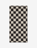 The Checkmate Bar Towel by Danelys Sidron, made of ultra-absorbent Geoweave fabric, showcases a black and off-white wavy checkerboard design that creates an optical illusion and is pictured flat on a white background.