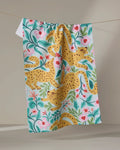 The Cheetah Haven kitchen towel by Jasmine Blooms Designs features yellow leopards, pink flowers, and green leaves, adding eco-friendly charm and vibrant style to your space.