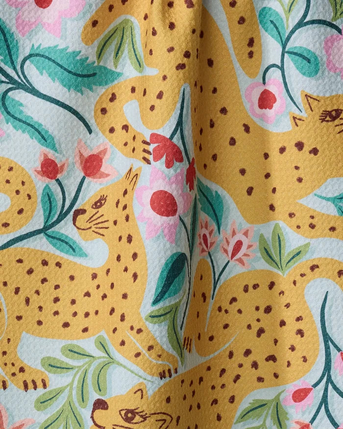 A close-up of the Cheetah Haven towel by Jasmine Blooms Designs, showcasing its ultra-absorbent texture and vibrant pattern of yellow cheetahs, green leaves, and pink flowers on a light background.