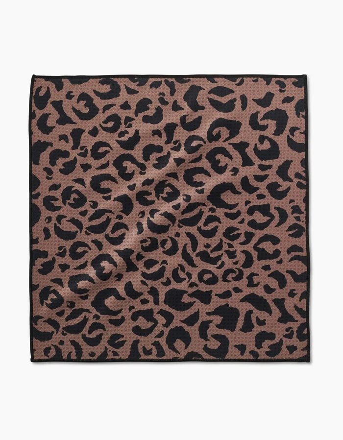 The Cheetah Hound Paw Towel by Geometry is a square towel made from ultra-absorbent Geoweave™ fabric, featuring a brown background with a black leopard print and a thin black border.