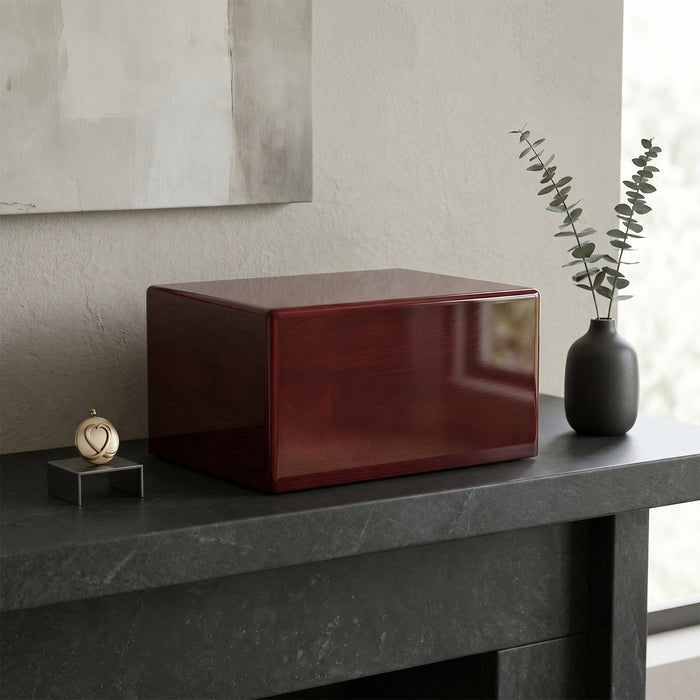 Red rectangular urn box on a dark surface with a vase and decorative item in the background.