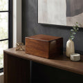 Wooden urn box on a wooden surface with decorative items in a room.