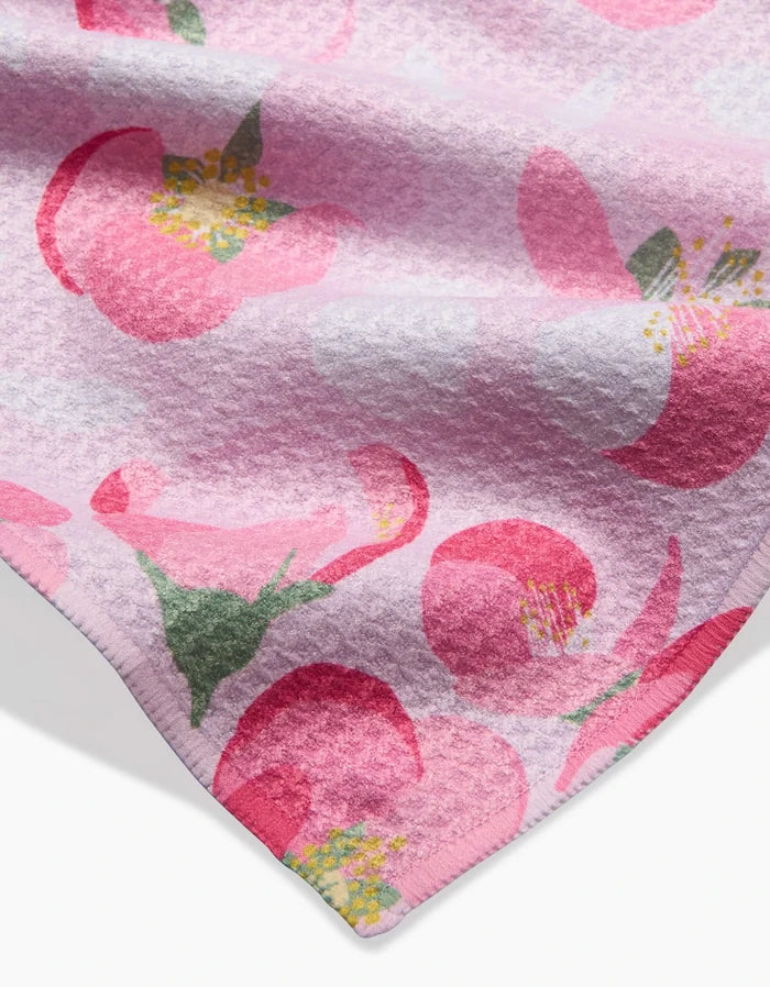 A close-up of the Cherry Blossom bar towel by Rebecca Bobko, showcasing plush textured fabric and a neat hem, with large stylized pink and green flowers with yellow centers.